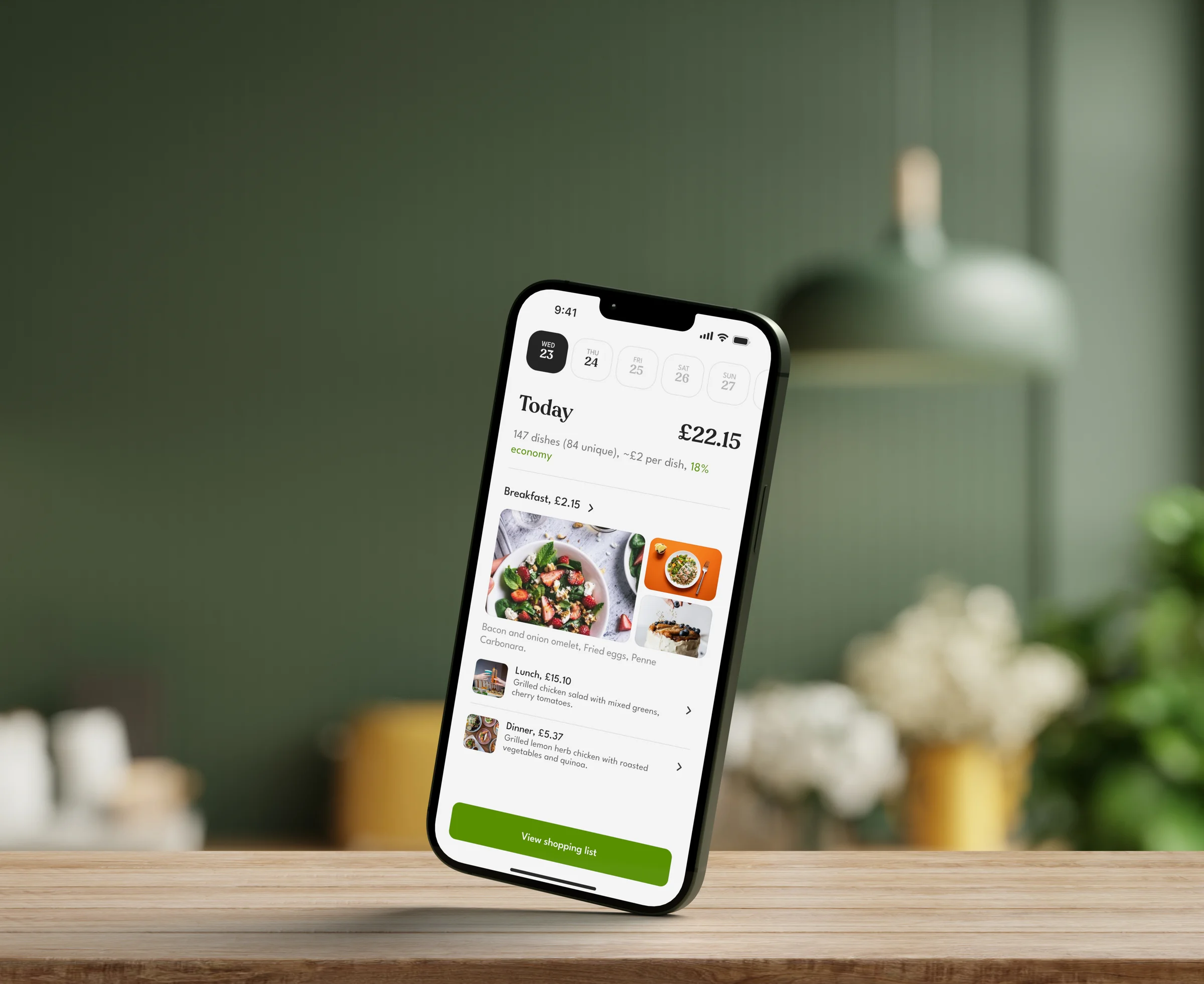 An iPhone standing on one corner on a kitchen table, showing a day of the meal plan with its cost
